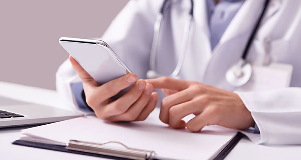 Symbolfoto: Ärztin informiert sich am Smartphone